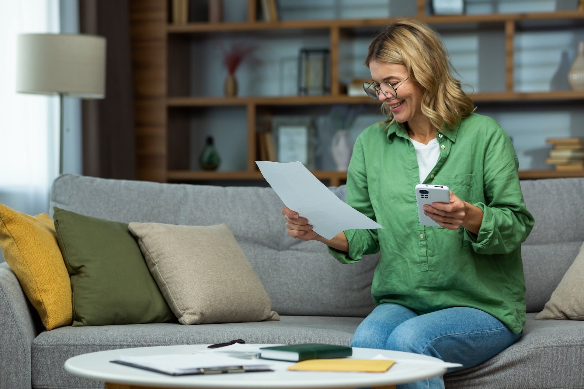 An elderly smilling woman sits at home on the sofa, researching whether home equity can help her achieve her retirement goals