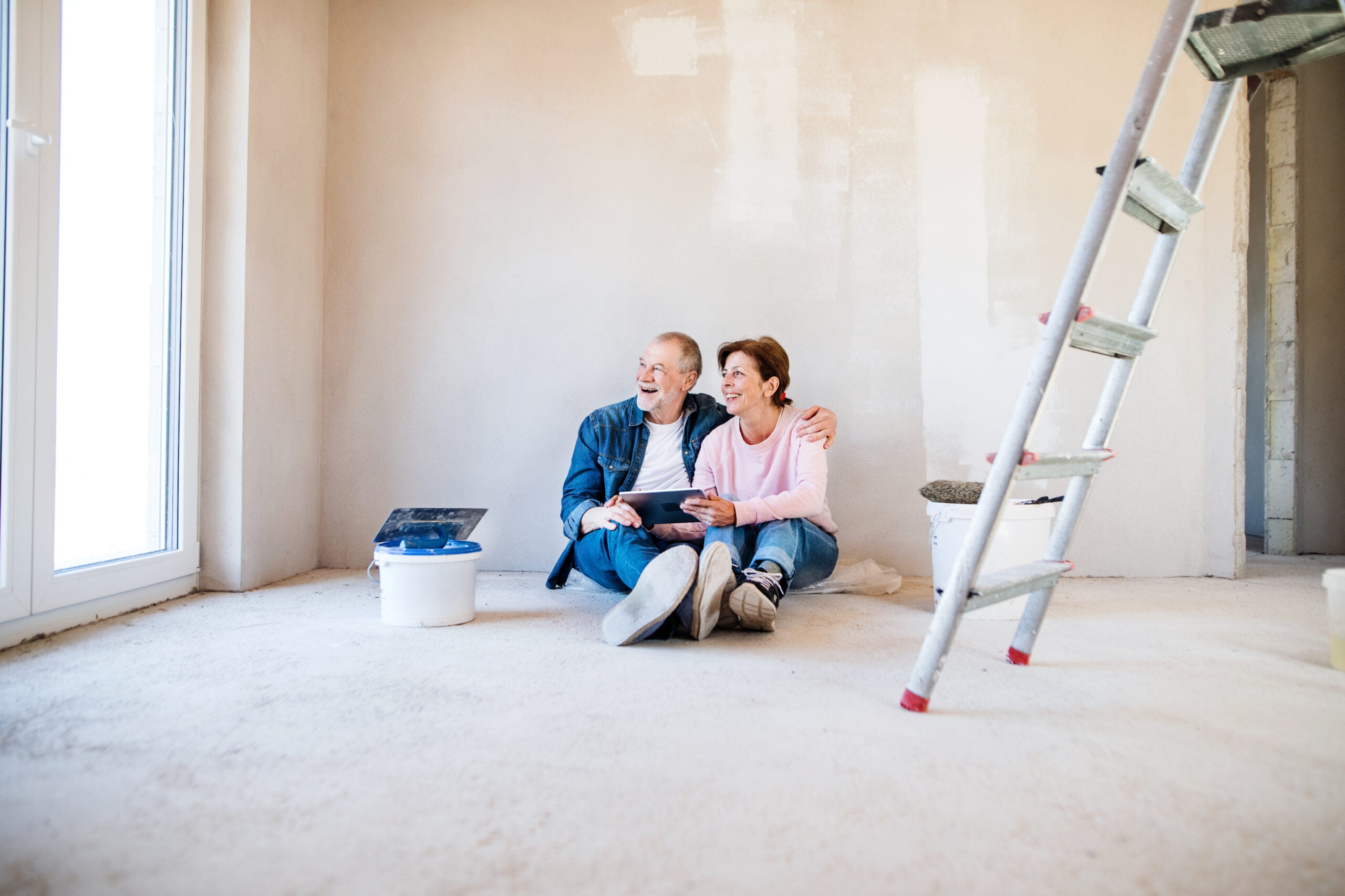 Older couple reviewing home improvement plans in a room under construction.