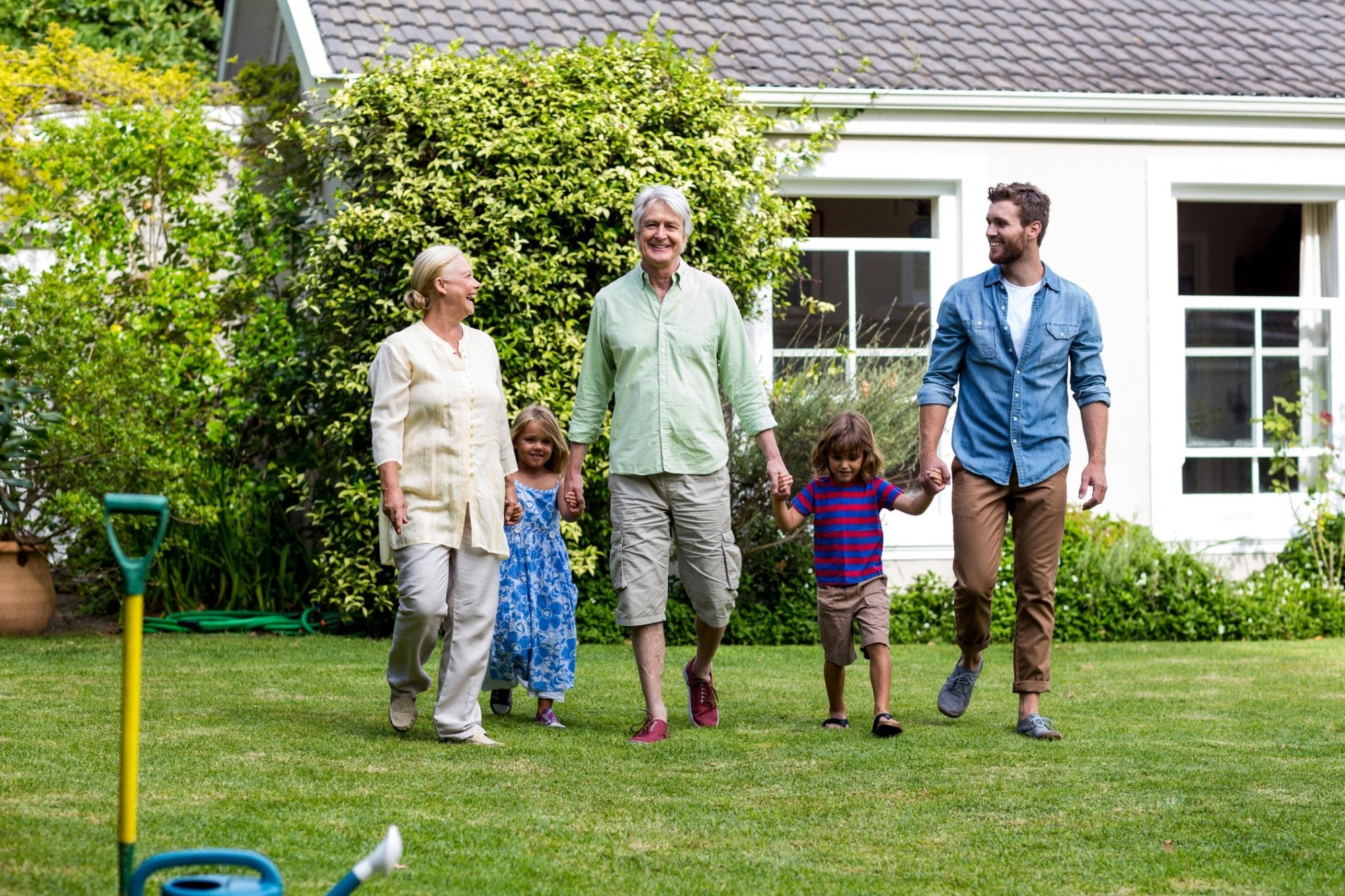 Older couple walking with family outside a home